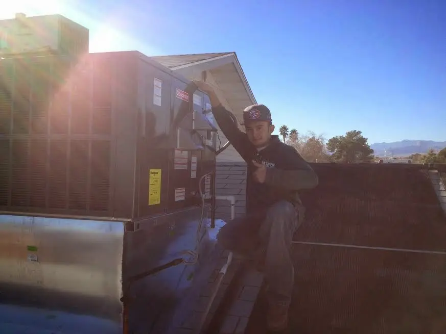 HVAC technician performing Air Duct Cleaning on a rooftop unit in Okmulgee